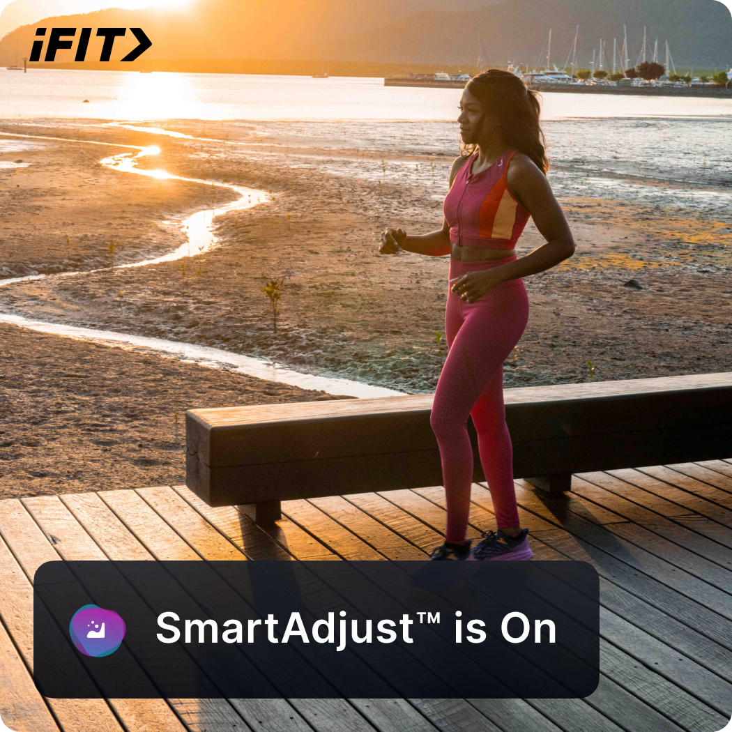 The iFIT app showing a runner on a boardwalk with a SmartAdjust is On notice